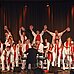 Der Chor OnceAgain bei einem Auftritt in weißer Kleigung und mit rotem Schal