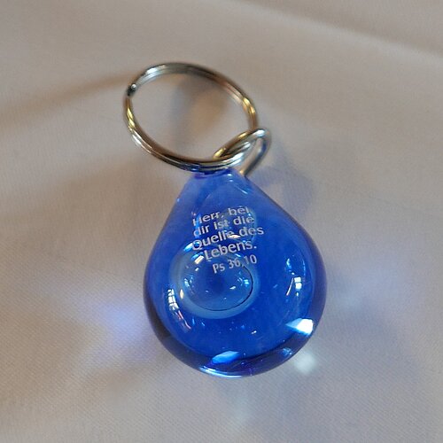 Ein Schlüsselanhänger in Form eines blauen Wassertropfens und der Aufschrift: Herr, bei dir ist die Quelle des Lebens. Psalm 36, 10