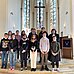 12 Konfirmandinnen und Konfirmanden mit Pfarrerin Britta Meyhoff vor dem Altar der Jakobi-Kirche