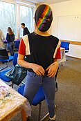 Mädchen hinter schwarzer Maske mit Regenbogen