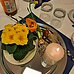 Auf einem silbernen Tablett ein Blumentopf mit gelben Primeln, Tupenzwiebeln mit einer blühenden Tupe, Weidenkätzchen und einer weißen brennenden Kerze